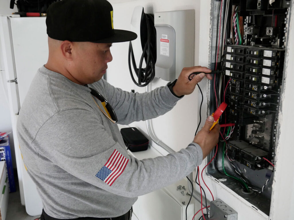 An electrician adjusts settings in an electrical panel, showcasing his expertise in comprehensive electrical services for both residential and commercial properties.