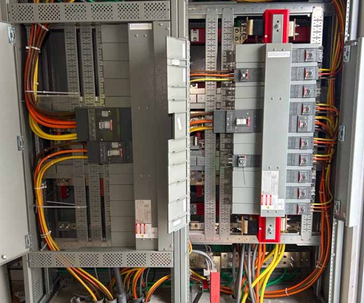 Open electrical panel in a commercial setting showing intricate configurations of color-coded wiring, essential for safety and functionality in electrical installations.